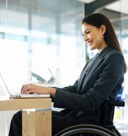 photo d'une femme en fauteuil roulant qui travaille sur un ordinateur